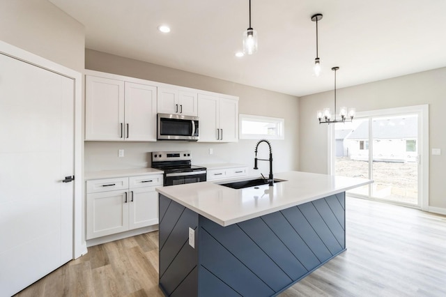 14512 Northpark Dr, Urbandale, IA 50111 - kitchen with stainless steel appliances, a sink, light wood-style floors, white cabinets, and healthy amount of natural light