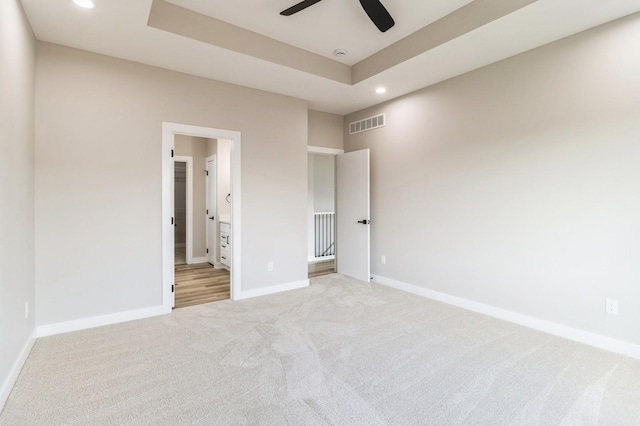 14512 Northpark Dr, Urbandale, IA 50111 - unfurnished bedroom with light colored carpet, recessed lighting, baseboards, ensuite bath, and a tray ceiling