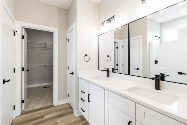 14512 Northpark Dr, Urbandale, IA 50111 - full bath with a walk in closet, double vanity, wood finished floors, baseboards, and a shower