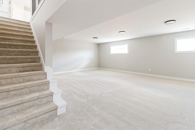 14512 Northpark Dr, Urbandale, IA 50111 - below grade area with stairway, baseboards, and light carpet