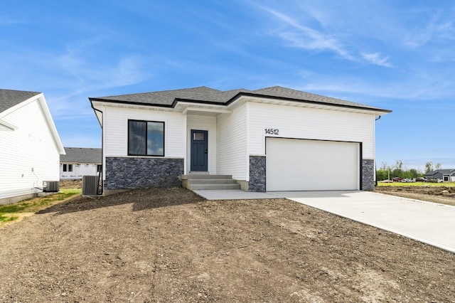 14512 Northpark Dr, Urbandale, IA 50111 - view of front of home featuring stone siding, concrete driveway, an attached garage, and central air condition unit
