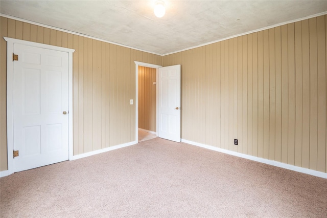 101 E Cronkhite St, Knoxville, IA 50138 - unfurnished bedroom featuring carpet floors, wooden walls, baseboards, and ornamental molding