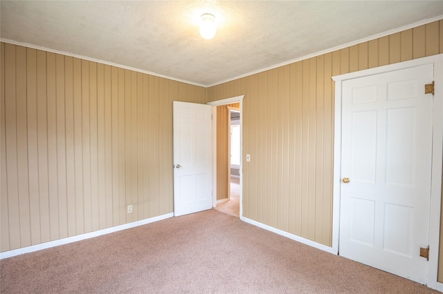 101 E Cronkhite St, Knoxville, IA 50138 - unfurnished bedroom featuring carpet flooring, ornamental molding, baseboards, and wood walls