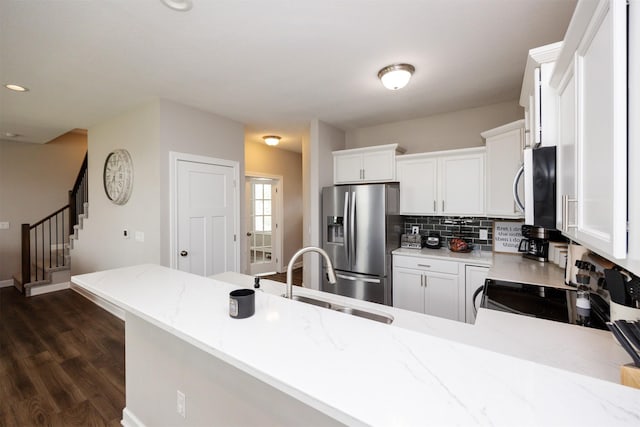 675 SE Maxwell Dr, Waukee, IA 50263 - kitchen featuring stainless steel appliances, dark wood finished floors, light stone countertops, a peninsula, and decorative backsplash