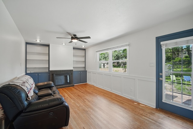 6700 Sheridan Ave, Des Moines, IA 50322 - living area with a ceiling fan, plenty of natural light, light wood finished floors, a fireplace, and wainscoting