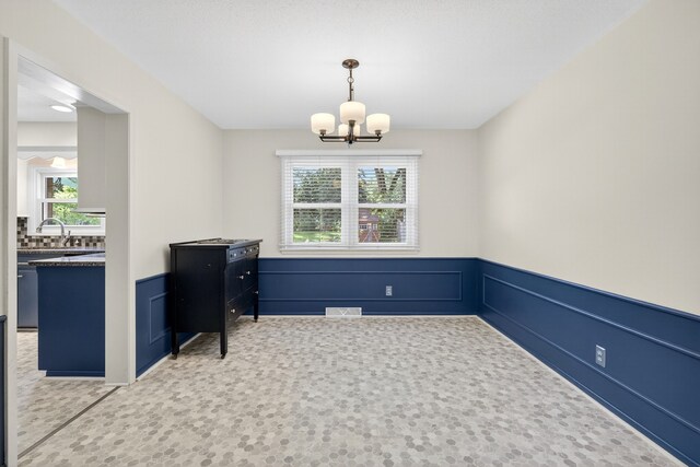 6700 Sheridan Ave, Des Moines, IA 50322 - unfurnished dining area with plenty of natural light, a chandelier, wainscoting, and carpet floors