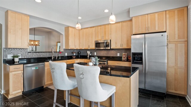 201 Grand Ave Unit 109, Des Moines, IA 50309 - kitchen with stainless steel appliances, light brown cabinets, a sink, dark countertops, and recessed lighting