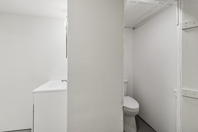 693 35th St, Des Moines, IA 50312 - bathroom featuring vanity, toilet, and a textured wall