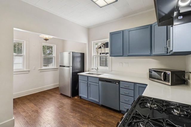 693 35th St, Des Moines, IA 50312 - kitchen with appliances with stainless steel finishes, a sink, light countertops, exhaust hood, and dark wood-style floors