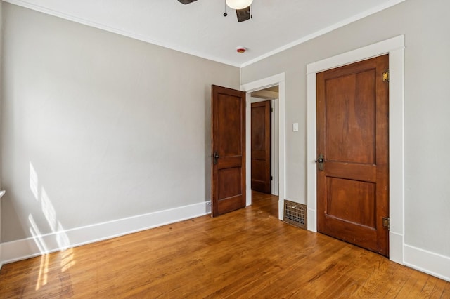 693 35th St, Des Moines, IA 50312 - unfurnished bedroom with wood finished floors, baseboards, ornamental molding, and a ceiling fan