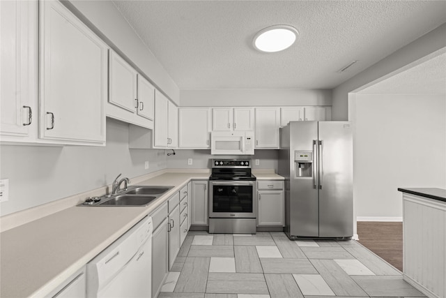 1240 49th St Unit 5, West Des Moines, IA 50266 - kitchen featuring appliances with stainless steel finishes, a sink, a textured ceiling, light countertops, and white cabinets