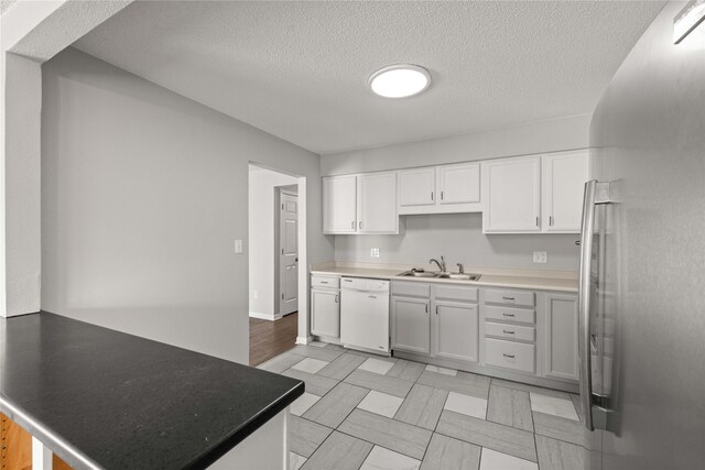 1240 49th St Unit 5, West Des Moines, IA 50266 - kitchen featuring dishwasher, a sink, a peninsula, white cabinets, and a textured ceiling