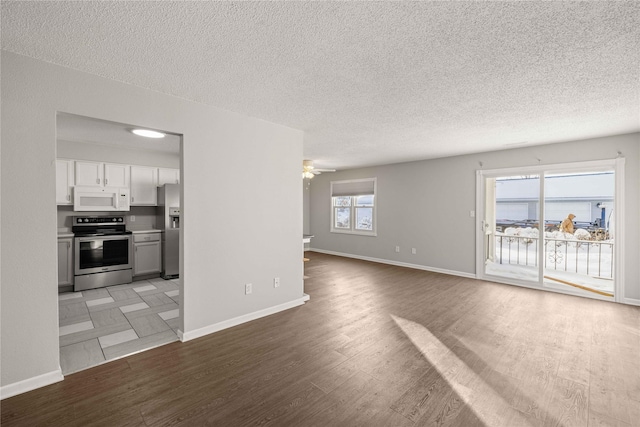 1240 49th St Unit 5, West Des Moines, IA 50266 - unfurnished living room with a textured ceiling, light wood-style floors, baseboards, and a ceiling fan