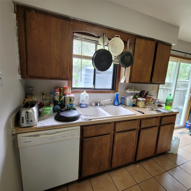 1850 King Ave, Des Moines, IA 50320 - kitchen with dishwasher, a sink, light countertops, light tile patterned floors, and brown cabinets
