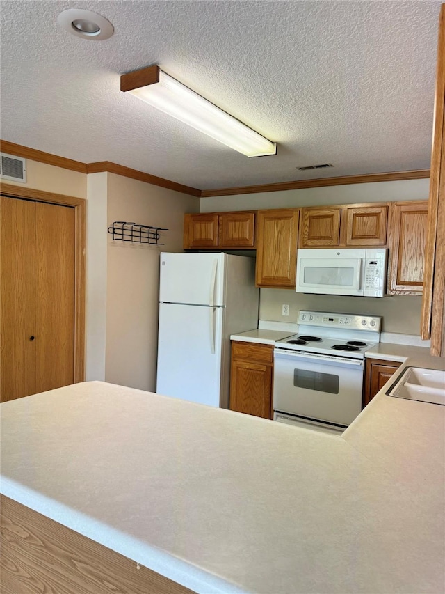10141 Sutton Dr Unit 7, Urbandale, IA 50322 - kitchen featuring white appliances, a textured ceiling, ornamental molding, light countertops, and brown cabinetry