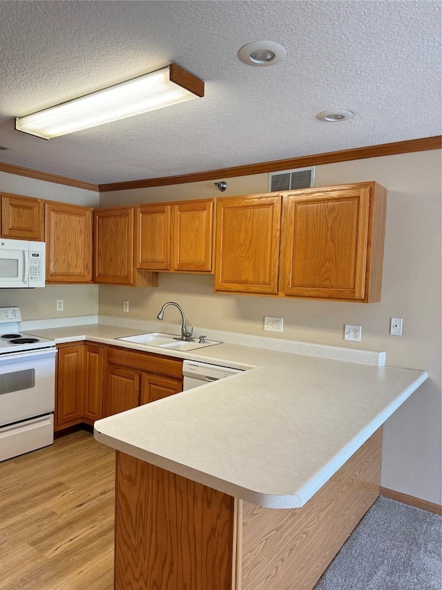 10141 Sutton Dr Unit 7, Urbandale, IA 50322 - kitchen with white appliances, a sink, light countertops, a peninsula, and a textured ceiling