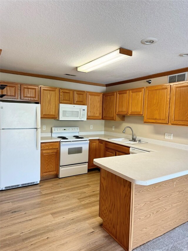10141 Sutton Dr Unit 7, Urbandale, IA 50322 - kitchen featuring white appliances, a sink, light countertops, a textured ceiling, and a peninsula