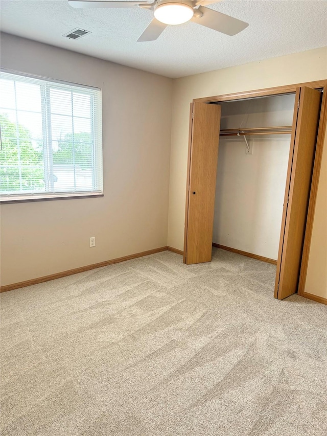 10141 Sutton Dr Unit 7, Urbandale, IA 50322 - unfurnished bedroom featuring light carpet, a closet, a ceiling fan, baseboards, and a textured ceiling