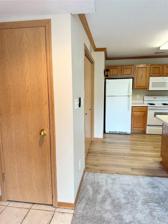 10141 Sutton Dr Unit 7, Urbandale, IA 50322 - kitchen featuring white appliances, light countertops, crown molding, brown cabinetry, and light carpet