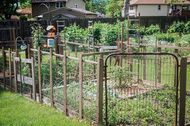 gate featuring a garden and a fenced backyard