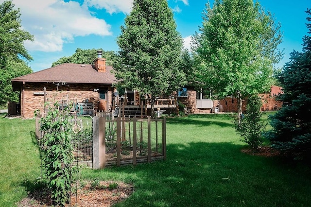 view of green lawn featuring a garden and a wooden deck