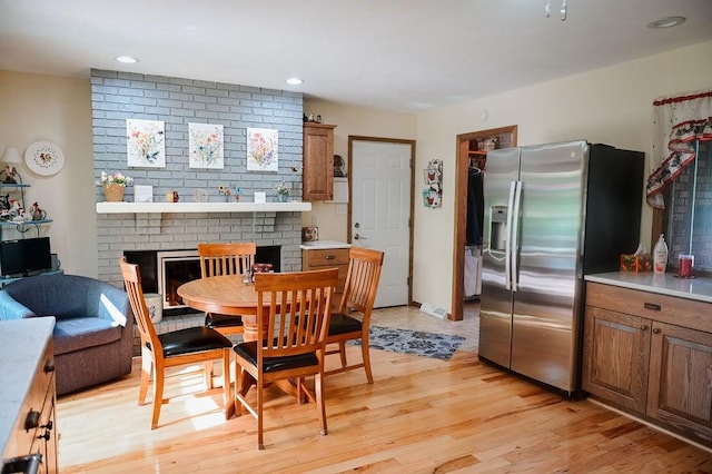 dining space featuring a fireplace, light wood-style floors, and recessed lighting