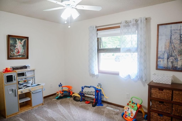 recreation room with a ceiling fan, carpet, and baseboards
