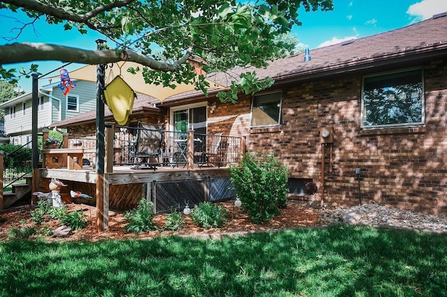 back of property with a jacuzzi, a wooden deck, brick siding, and roof with shingles