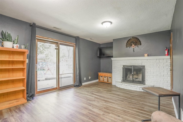 406 NW Kimberly Ln, Ankeny, IA 50023 - living area with wood finished floors, a textured ceiling, a brick fireplace, and baseboards