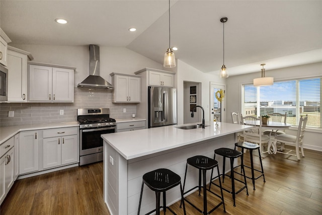 980 Daybreak Dr, Waukee, IA 50263 - kitchen with stainless steel appliances, wall chimney exhaust hood, a sink, vaulted ceiling, and a breakfast bar