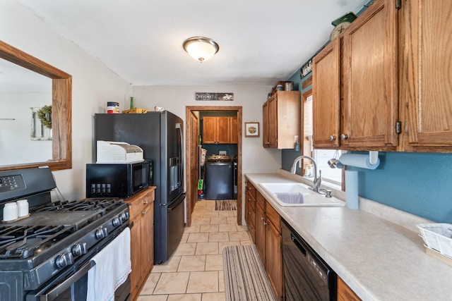 225 NW 50th Pl, Des Moines, IA 50313 - kitchen with black appliances, a sink, light countertops, brown cabinets, and washer / clothes dryer