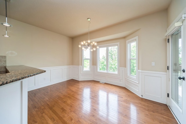 1420 Hannah Ln, Waukee, IA 50263 - unfurnished dining area with a wainscoted wall, light wood-type flooring, a chandelier, and a decorative wall
