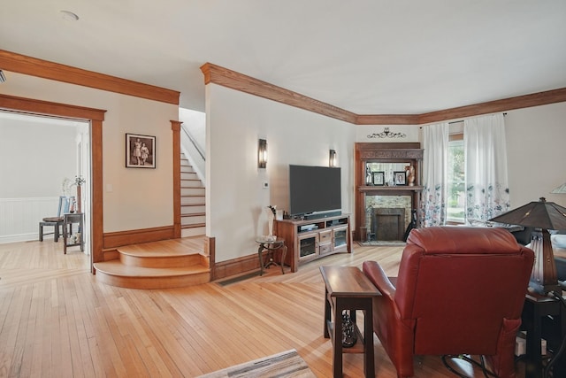 207 Kellogg Ave, Dallas Center, IA 50063 - living area featuring stairway, a fireplace with raised hearth, light wood-style floors, baseboards, and crown molding