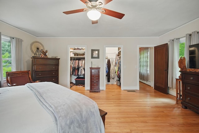 207 Kellogg Ave, Dallas Center, IA 50063 - bedroom with light wood-style flooring, a spacious closet, a ceiling fan, a baseboard heating unit, and baseboards
