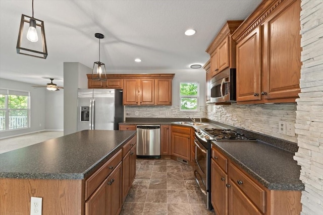 kitchen featuring appliances with stainless steel finishes, dark countertops, a sink, healthy amount of natural light, and recessed lighting