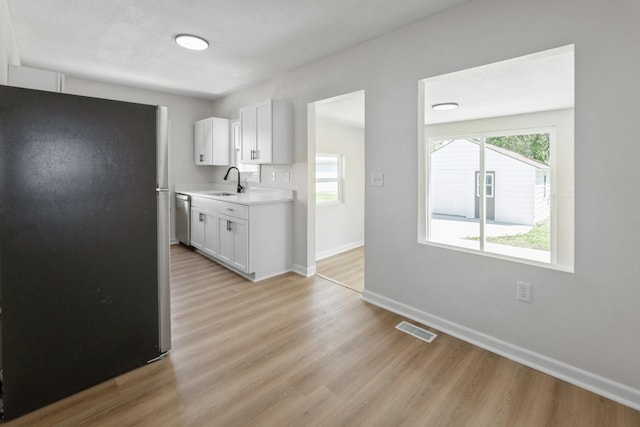 2311 50th St, Des Moines, IA 50310 - kitchen with stainless steel appliances, a sink, light wood-style floors, light countertops, and baseboards