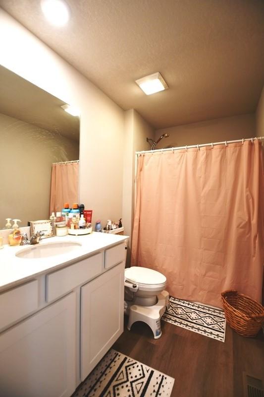 2010 N 7th St, Indianola, IA 50125 - full bath featuring wood finished floors, toilet, and vanity
