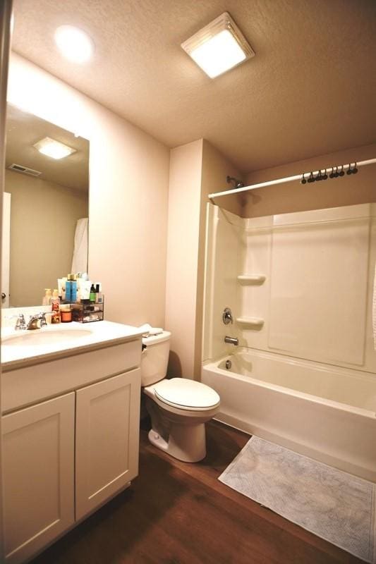 2010 N 7th St, Indianola, IA 50125 - full bath featuring wood finished floors, bathtub / shower combination, toilet, vanity, and a textured ceiling