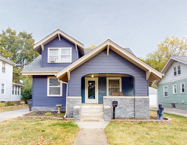 1415 46th St, Des Moines, IA 50311 - view of front of home with stone siding, a front yard, covered porch, and roof with shingles