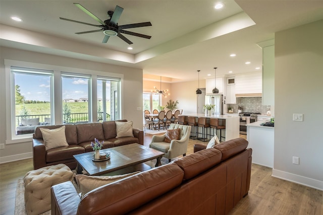 2770 NW 167th St, Clive, IA 50325 - living area with light wood-style flooring, ceiling fan, recessed lighting, a chandelier, and a tray ceiling