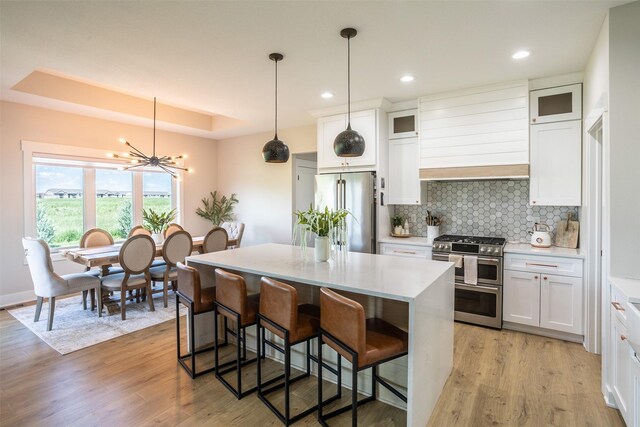 2770 NW 167th St, Clive, IA 50325 - kitchen featuring stainless steel appliances, a kitchen island, white cabinets, light wood-style flooring, and tasteful backsplash