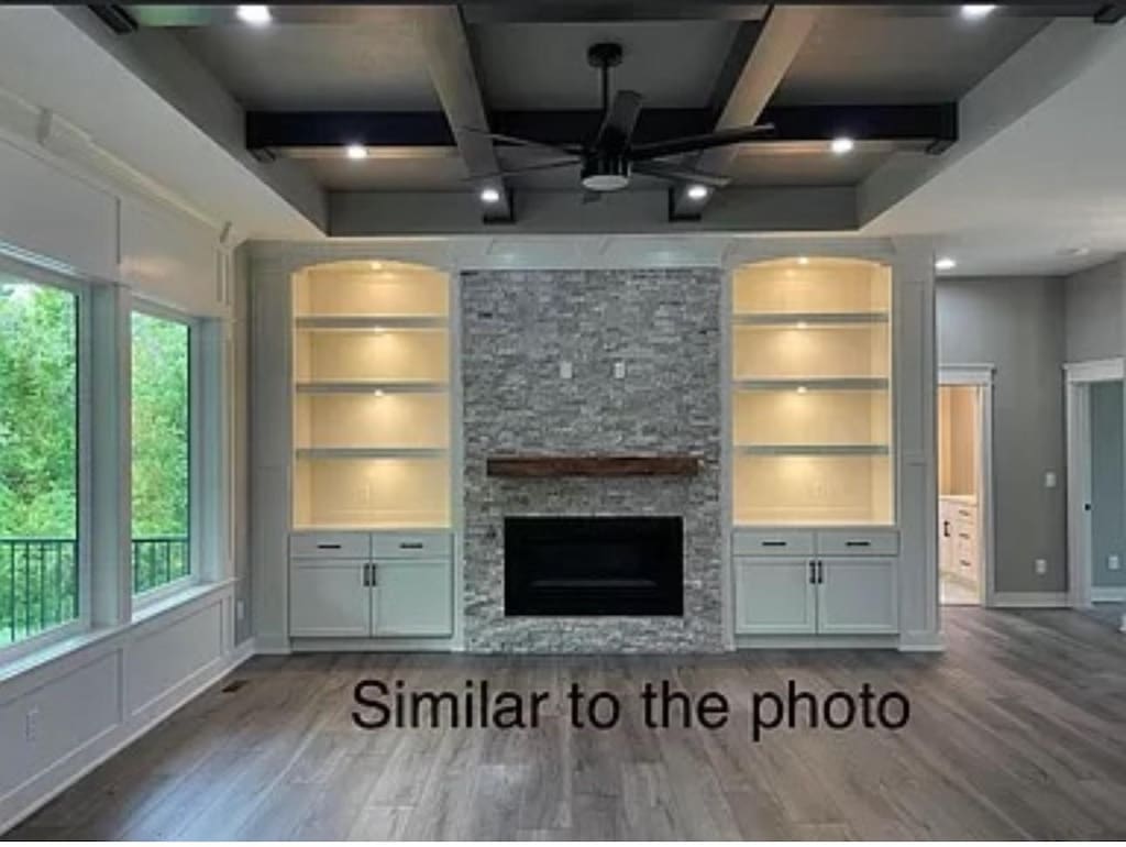 18099 Townsend Dr, Clive, IA 50325 - unfurnished living room with wood finished floors, built in features, beam ceiling, a stone fireplace, and coffered ceiling