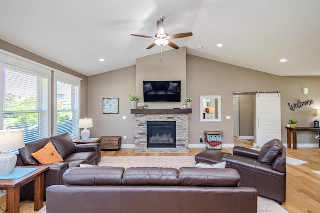 living area with a barn door, ceiling fan, light wood finished floors, lofted ceiling, and baseboards