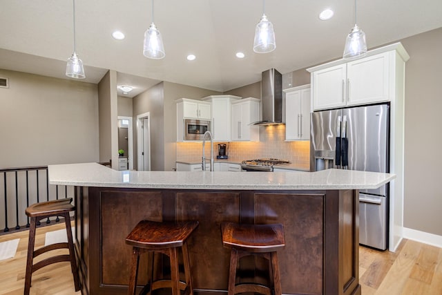 kitchen featuring wall chimney exhaust hood, stainless steel appliances, light wood-type flooring, decorative backsplash, and recessed lighting