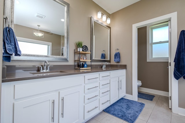 bathroom featuring plenty of natural light, toilet, double vanity, and tile patterned floors