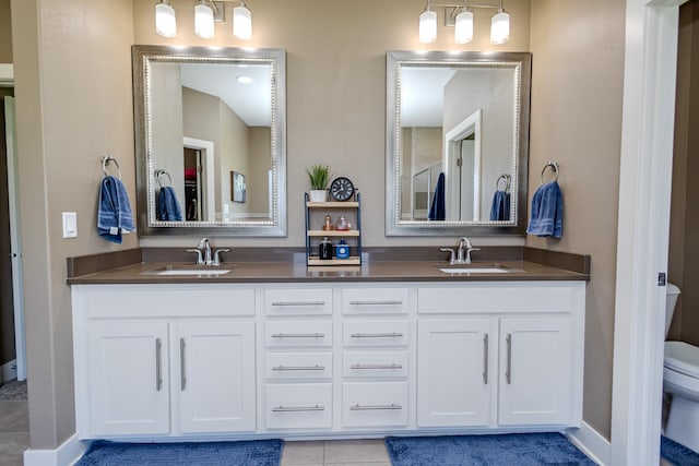 full bath featuring toilet, double vanity, tile patterned flooring, and baseboards