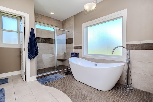 full bathroom featuring tile walls, a shower stall, tile patterned floors, a freestanding tub, and a wainscoted wall