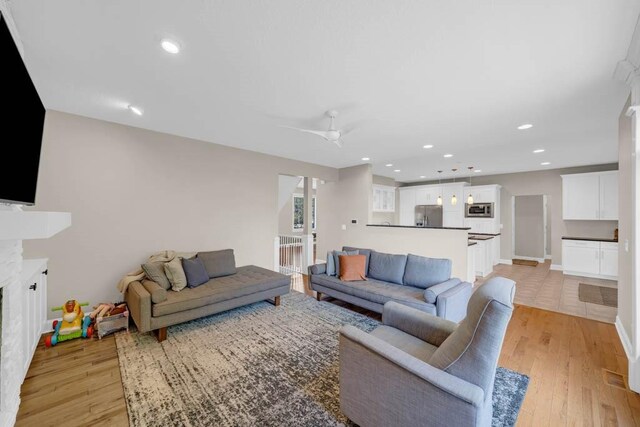 947 11th Ave SE, Altoona, IA 50009 - living room with light wood-style floors, ceiling fan, recessed lighting, a fireplace, and baseboards