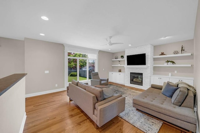 947 11th Ave SE, Altoona, IA 50009 - living room featuring a ceiling fan, a stone fireplace, light wood-style floors, baseboards, and recessed lighting