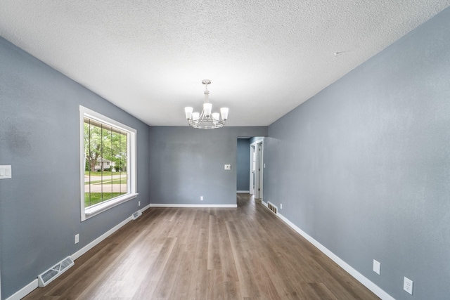 208 Van Buren Dr, Van Meter, IA 50261 - spare room featuring a chandelier, wood finished floors, baseboards, and a textured ceiling